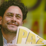 Foto del rostro de Iván Cepeda, sonriente y con un banderín de la paz