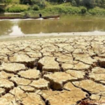 Imagen de tierra seca y al fondo un río mermado en su cauce