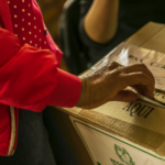 Mano femenina depositando un voto en una urna