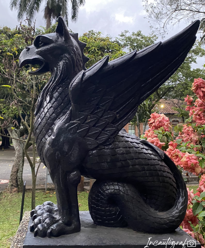 Escultura negra de perfil de un monstruo con orejas, pico y alas.