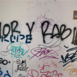 Pared pintada con muchos grafitis entre los que sobresale uno que dice amor y rabia.