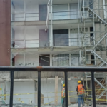 Edificio averiado por terremoto. Andamios y gente reparándolo