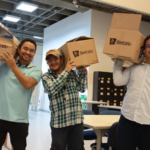 Tres hombres con cajas en sus hombros.