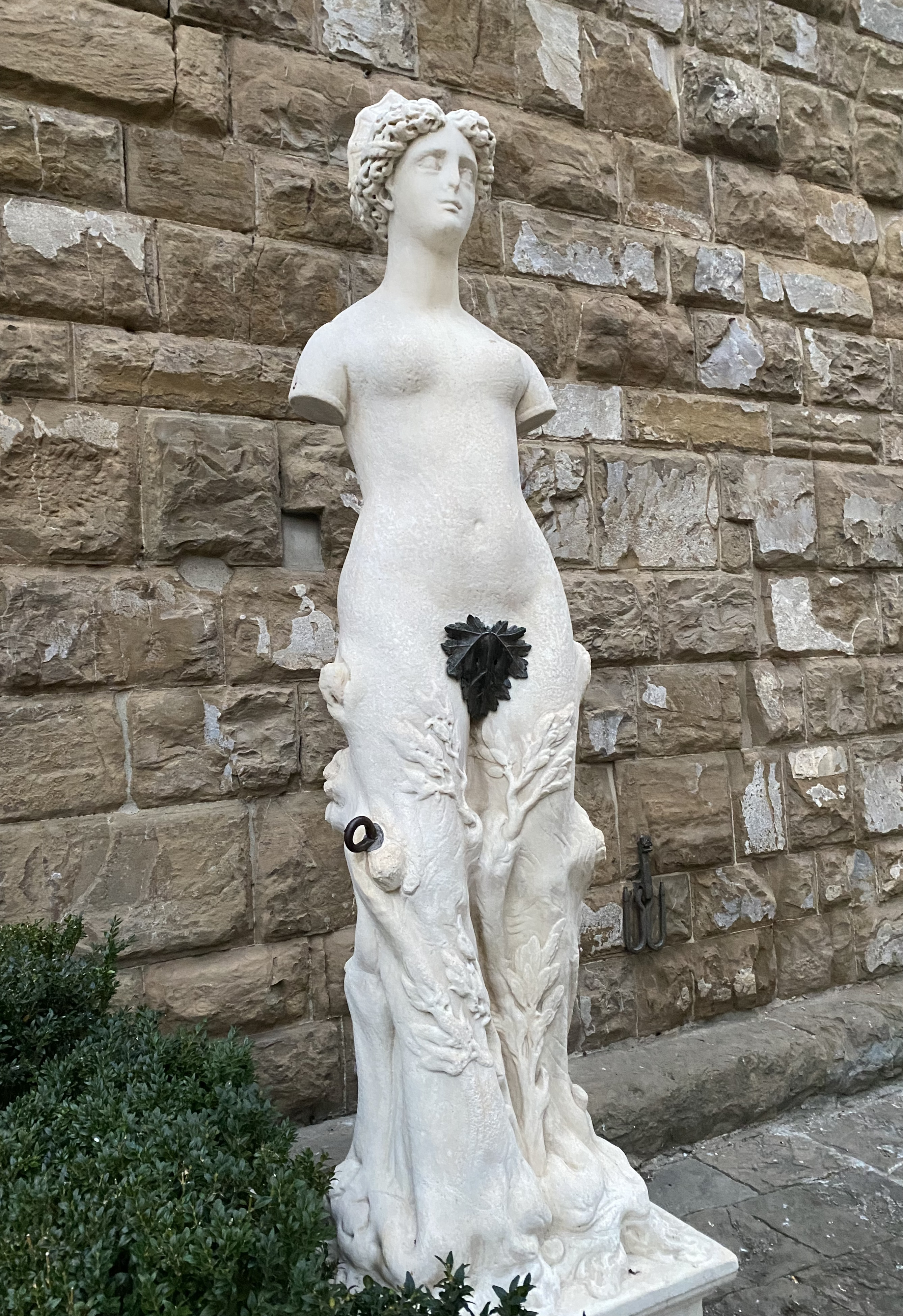 Escultura de una mujer con el pubis cubierto por una planta