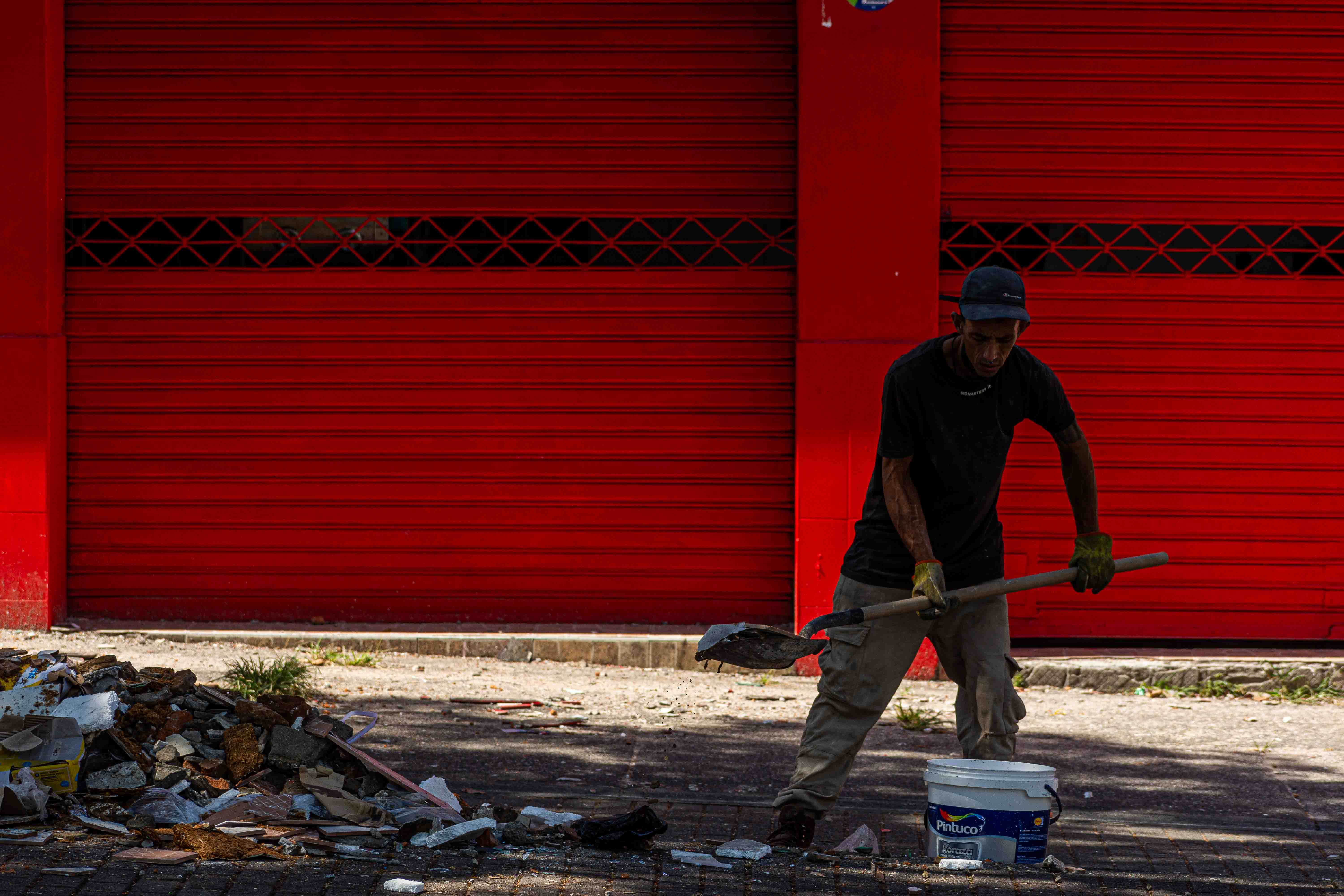 Un hombre retira escombros del frente de un local comercial colapsado. Carrera 8 calle 25 en el centro de Pereira. Al fondo una puerta roja.