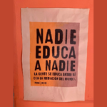 Afiche pegado en una pared que dice Nadie Educa a Nadie,