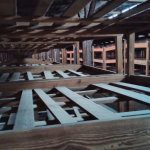 Foto del complejo Auschwitz – Birkenau en la que se ve una serie de camastros sin colchón, andamiajes de maderas en donde presumimos dormían los prisioneros.