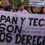 Imagen de la marcha del 14 de octubre de una personas con una pancarta grande que dice Tierra pan y techo son nuestros derechos.