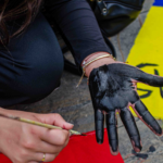 Foto de una persona que se pinta una mano de color negro durante las marchas en Manizales.