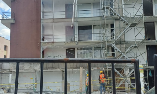 Edificio averiado por terremoto. Andamios y gente reparándolo