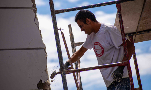Un hombre golpea la fachada de un edificio de la plaza de Bolivar para desprender los pedazos afectados.