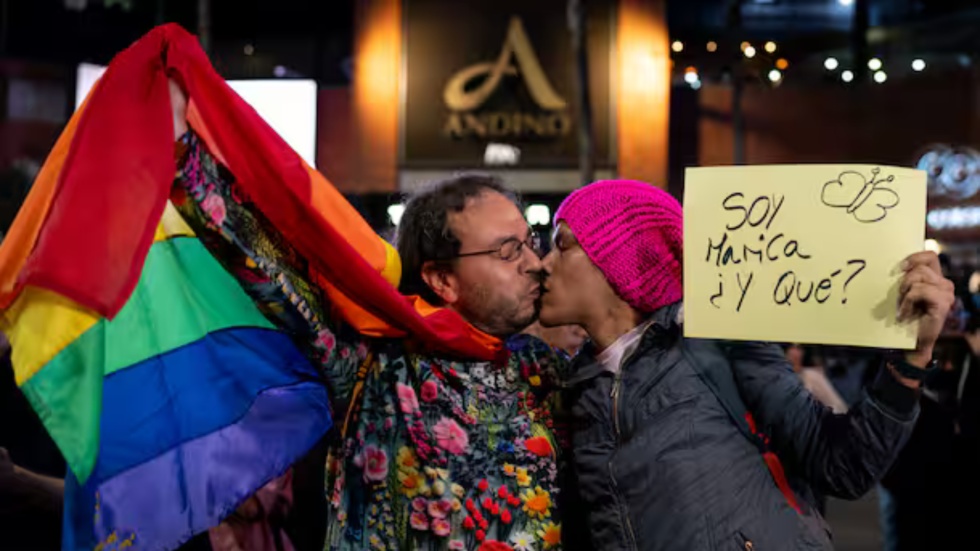 Imagen de dos hombres besándose, con la bandera gay