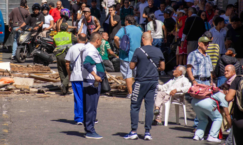 Ancianos en la calle y al fondo escombros de terremoto