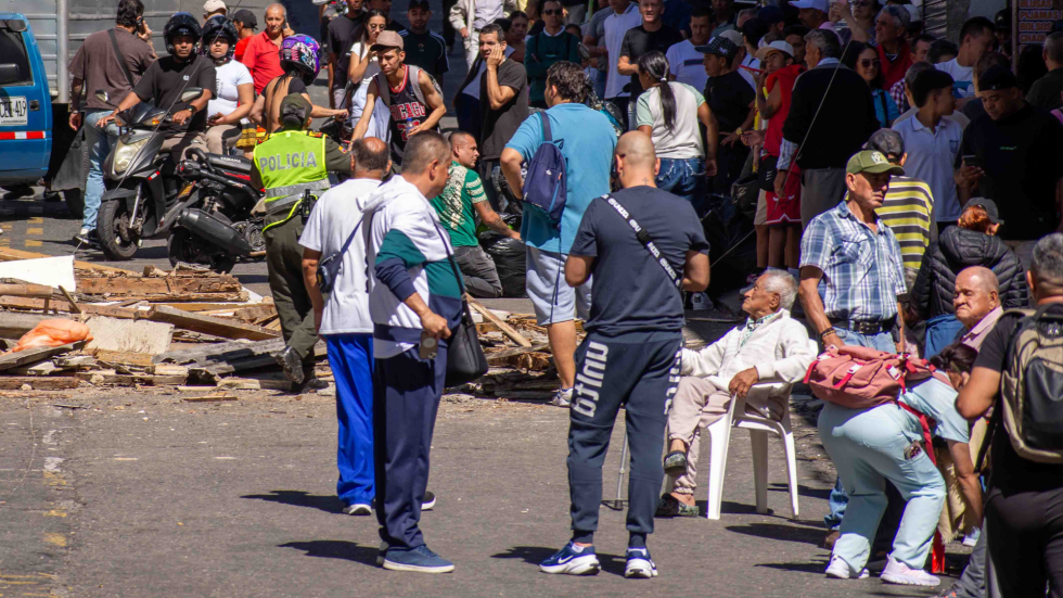 Ancianos en la calle y al fondo escombros de terremoto