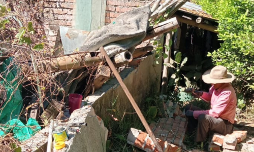 Hombre trabajando sobre una casa en ruinas