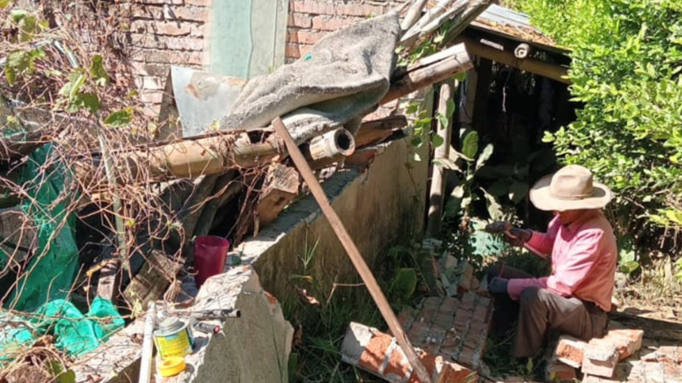 Hombre trabajando sobre una casa en ruinas