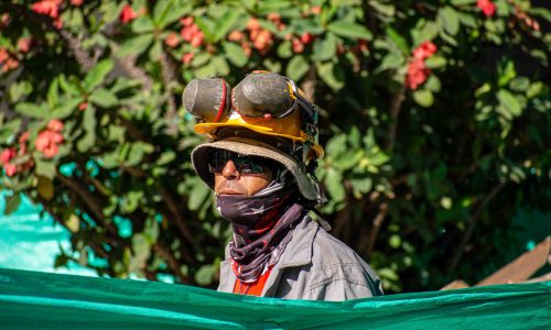 Obrero con gafas, casco y protección en los oídos.