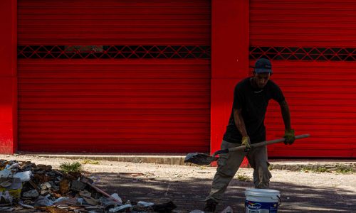 Un hombre retira escombros del frente de un local comercial colapsado. Carrera 8 calle 25 en el centro de Pereira. Al fondo una puerta roja.