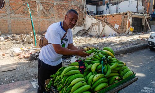 Vendedor de plátanos y detrás una casa destruida