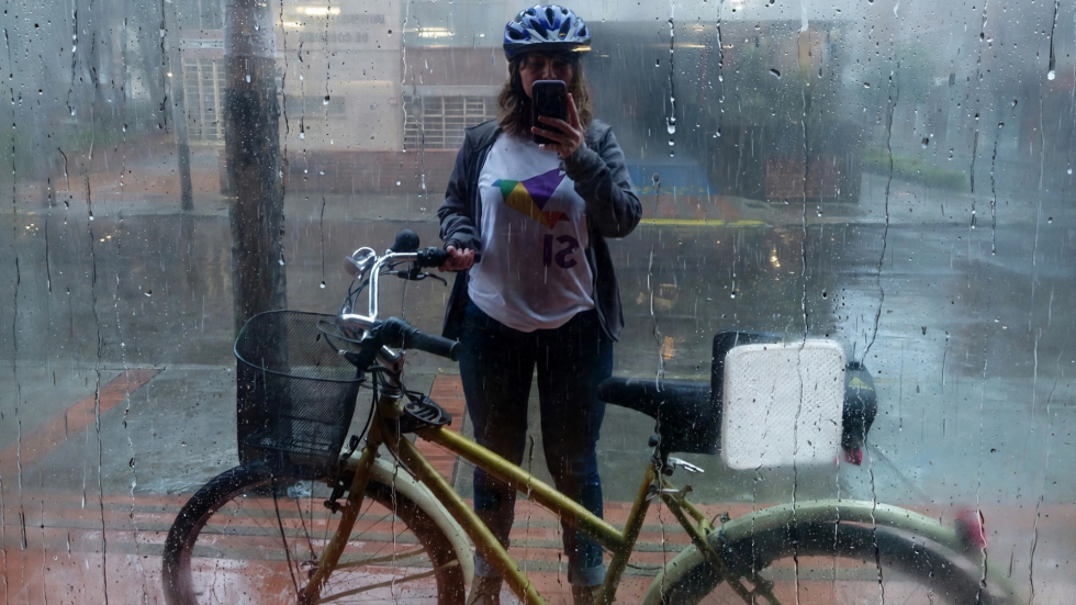 En la foto se ve a Yenny de pie tomándo una selfie mientras sostiene su bicicleta. Tiene puesta la camiseta con una paloma de origami de colores y con la palabra Sí, a favor del plebiscito de 2016 por la paz.