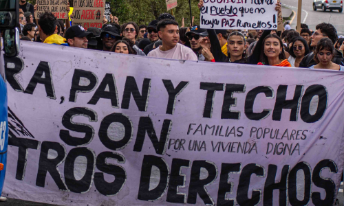 Imagen de la marcha del 14 de octubre de una personas con una pancarta grande que dice Tierra pan y techo son nuestros derechos.