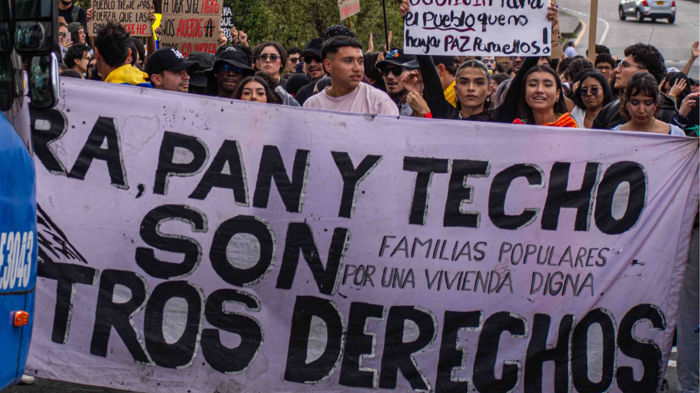 Imagen de la marcha del 14 de octubre de una personas con una pancarta grande que dice Tierra pan y techo son nuestros derechos.