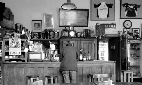 Foto del Bar Las Heras en el que se ven mesas, el mostrador, y una persona dando la espalda. Asumimos que es uno de los personajes mencionados en el texto.