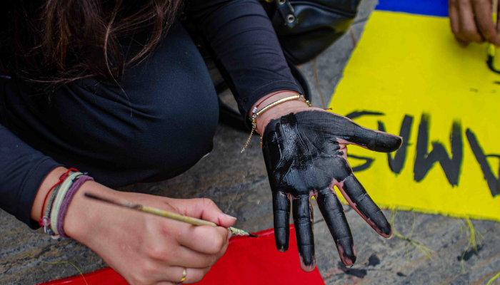 Foto de una persona que se pinta una mano de color negro durante las marchas en Manizales.
