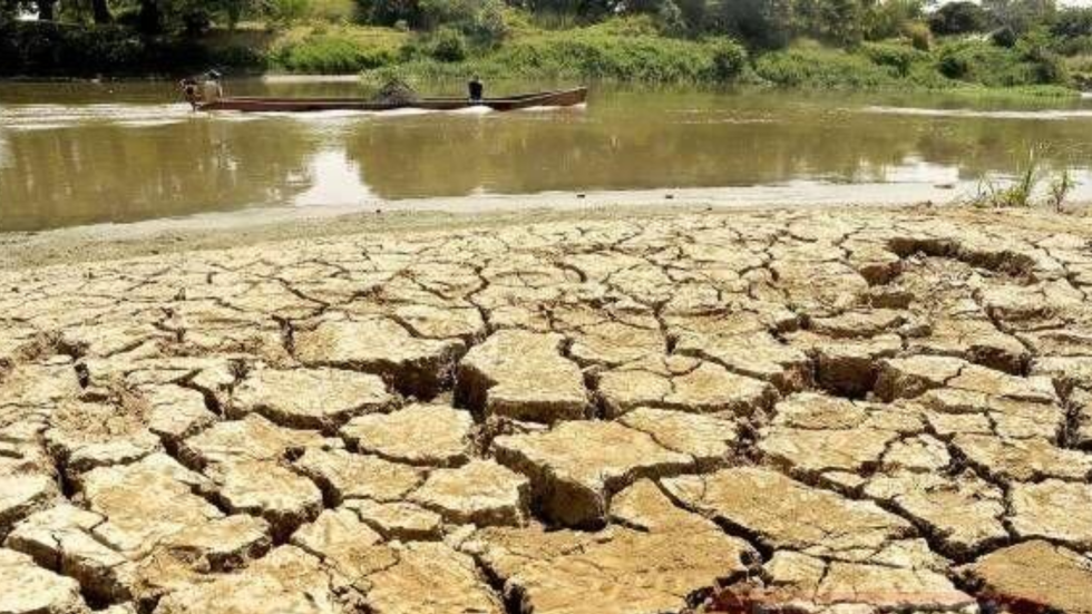 Imagen de tierra seca y al fondo un río mermado en su cauce