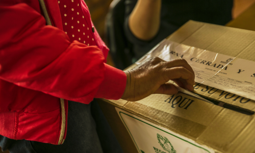 Mano femenina depositando un voto en una urna