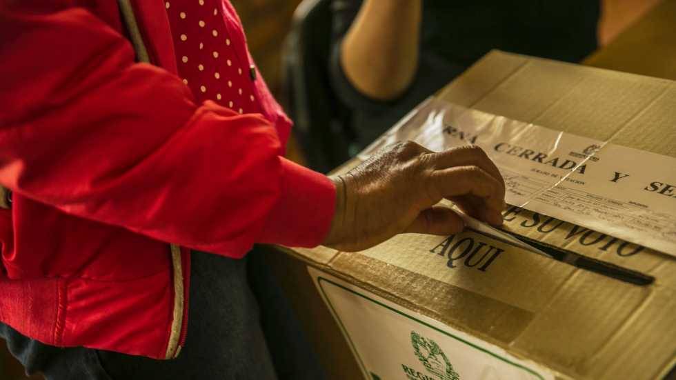 Mano femenina depositando un voto en una urna