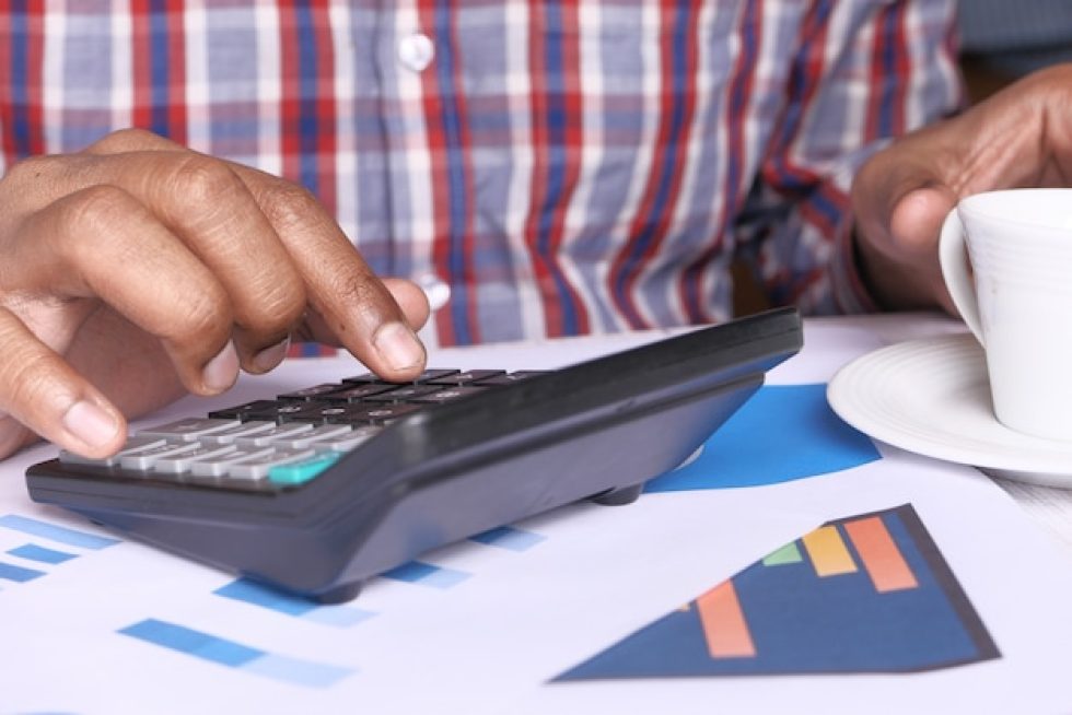 persona-mano-usando-calculadora-escritorio_260672-235-2860656152