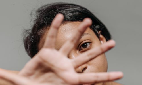 Una mujer con el gesto de "para" con la mano al frente de la cara.