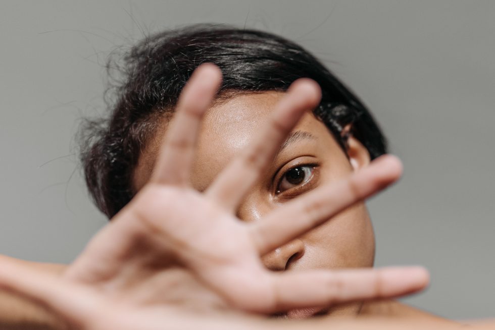 Una mujer con el gesto de "para" con la mano al frente de la cara.